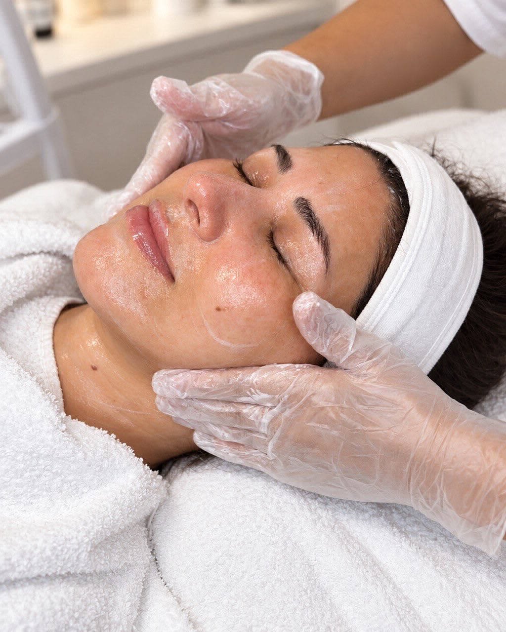 Gesichtsbehandlung bei Jamila Beauty: Pflege wird mit Handschuhen auf Wange und Kinn aufgetragen